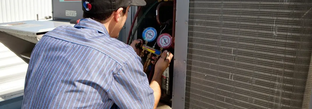 HVAC technician servicing a condenser unit in Pinewood